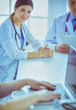 Ciddi bir tıbbi ekip parlak bir ofiste dizüstü bilgisayar kullanıyor.