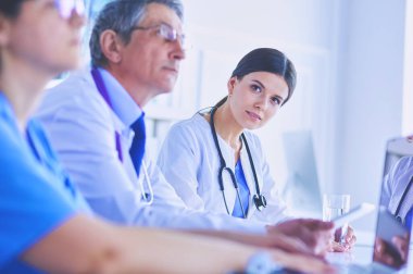 Ciddi bir tıbbi ekip parlak bir ofiste dizüstü bilgisayar kullanıyor.