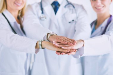 Doktorlar ve hemşireler tıbbi bir ekipte el ele tutuşuyorlar..