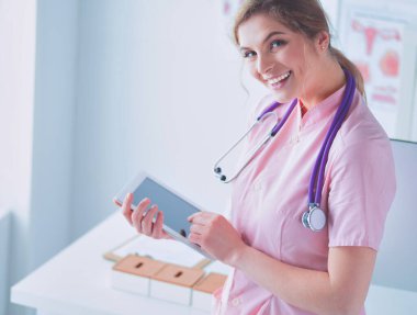 Hastanede tablet bilgisayar kullanan güzel bir kadın sağlık görevlisi..