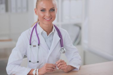 Masada oturan gülümseyen güzel genç bayan doktor.