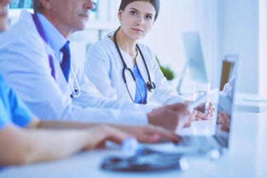 Ciddi bir tıbbi ekip parlak bir ofiste dizüstü bilgisayar kullanıyor.