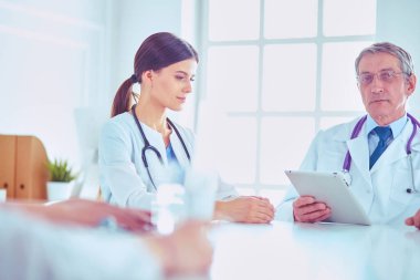 Ciddi bir tıbbi ekip parlak bir ofiste dizüstü bilgisayar kullanıyor.