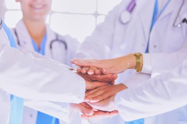 Doktorlar ve hemşireler tıbbi bir ekipte el ele tutuşuyorlar..