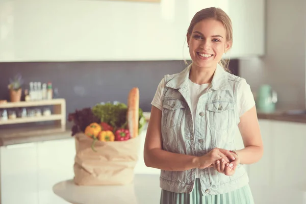 拿着蔬菜购物袋的年轻妇女 站在厨房里 — 图库照片