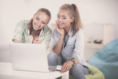 alışveriş çantası ile evde oturan iki genç kadın.