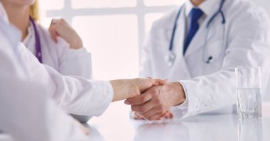 Doktor ofiste erkek bir hastayla el sıkışıyor..