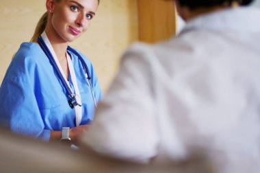 Bir doktor konuşuyor ve bir hastayı muayene ediyor..