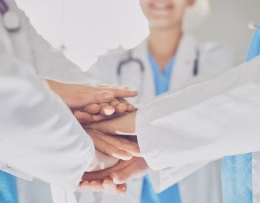 Doktorlar ve hemşireler tıbbi bir ekipte el ele tutuşuyorlar..