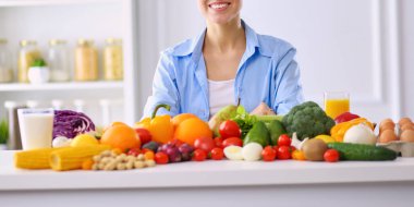 Ahşap iç kısımda meyve ve sebze dolu masada oturan genç ve tatlı bir kadın.