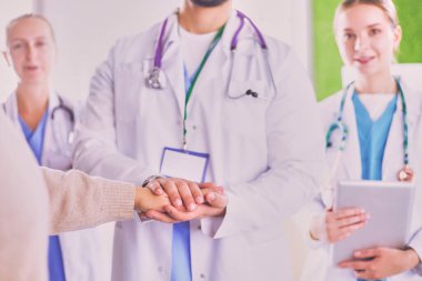 Doktorlar ve hemşireler tıbbi bir ekipte el ele tutuşuyorlar..