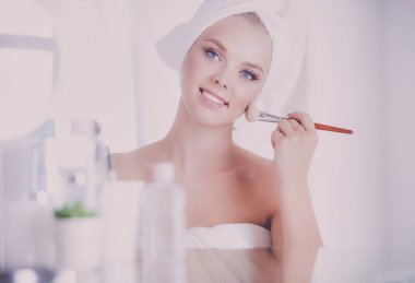 Genç bir kadının banyoya yüz pudrası sürerken fotoğrafı..