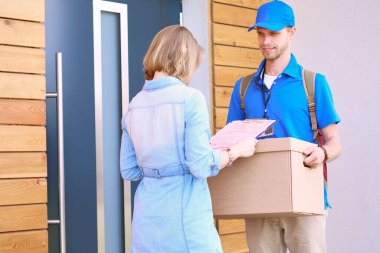 Mavi üniformalı gülümseyen kurye servis konseptine paket kutusu teslim eden teslimatçı. Mavi üniformalı gülümseyen teslimatçı..