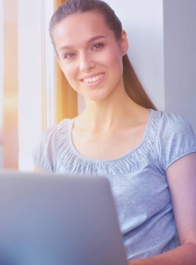 Evde bir dizüstü bilgisayar kullanan genç güzel kadın. Genç güzel kadın