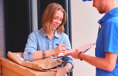 Mavi üniformalı gülümseyen kurye servis konseptine paket kutusu teslim eden teslimatçı. Mavi üniformalı gülümseyen teslimatçı..