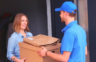 Mavi üniformalı gülümseyen kurye servis konseptine paket kutusu teslim eden teslimatçı. Mavi üniformalı gülümseyen teslimatçı..