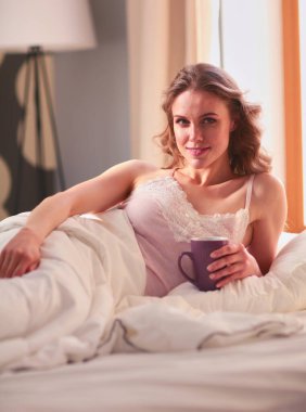 Genç kadın yatakta yatan ise kahve veya çay içme