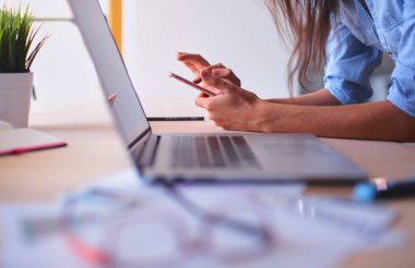 Ofis masasında oturan ve cep telefonuyla konuşan genç ve güzel bir iş kadını. İş kadını.