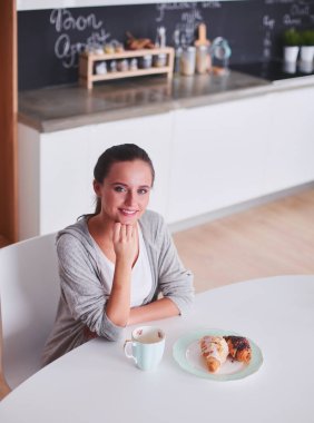 Mutfak masasında tatlı kruvasan ile çay içme kadın