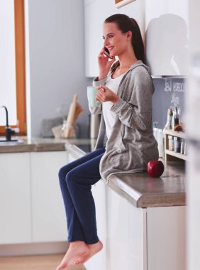 modern mutfakta otururken cep telefonu kullanan kadın