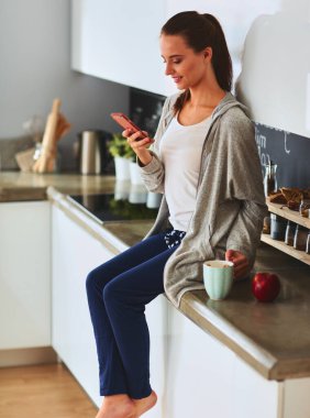 modern mutfakta otururken cep telefonu kullanan kadın.