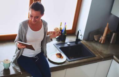 Mutfakta dijital tablet kullanan güzel genç bir kadın..