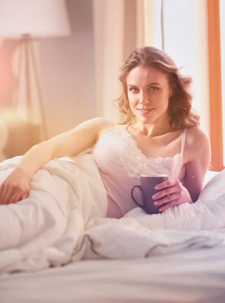 Genç Kadın Yatakta Yatan Ise Kahve Veya Çay Içme — Stok fotoğraf