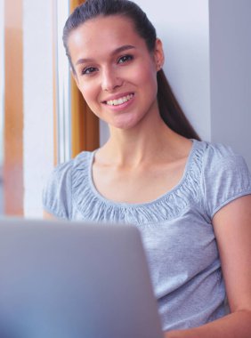 Evde bir dizüstü bilgisayar kullanan genç güzel kadın. Genç güzel kadın