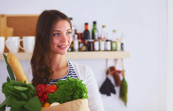 Νεαρή Γυναίκα Κρατώντας Παντοπωλείων Καλάθι Λαχανικά Στέκεται Στην Κουζίνα Νεαρή — Φωτογραφία Αρχείου