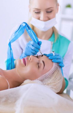 Kaşlar için kalıcı makyaj. Güzellik salonunda kalın kaşlı güzel bir kadın..