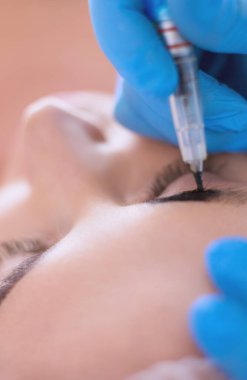 Kaşlar için kalıcı makyaj. Güzellik salonunda kalın kaşlı güzel bir kadın..