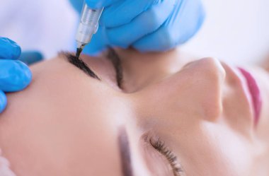 Kaşlar için kalıcı makyaj. Güzellik salonunda kalın kaşlı güzel bir kadın..