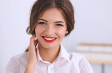 Ofiste duvarın yanında duran çekici bir iş kadını..