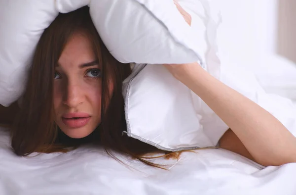 女性躺在床上 用枕头捂住耳朵 — 图库照片