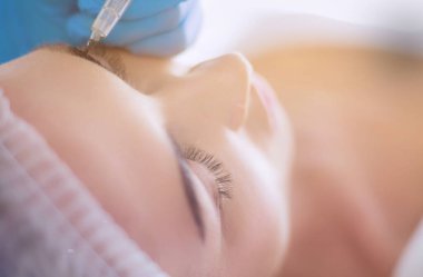 Kaşlar için kalıcı makyaj. Güzellik salonunda kalın kaşlı güzel bir kadın..