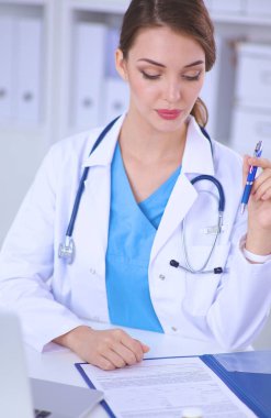 Kadın doktor masada oturuyor ve dizüstü bilgisayarla çalışıyor..