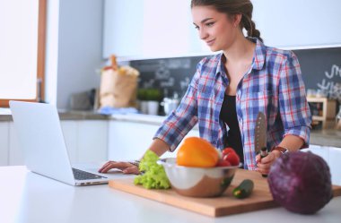 Gülümseyen kadın mutfakta tablet ve kredi kartı kullanarak alışveriş online .