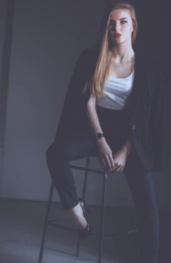 Genç bir kadın sandalyede oturuyor. .