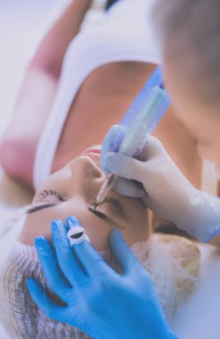 Kaşlar için kalıcı makyaj. Güzellik salonunda kalın kaşlı güzel bir kadın..