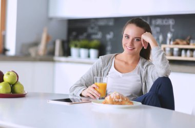 Gülümseyen kadın mutfakta tablet ve kredi kartı kullanarak alışveriş online .
