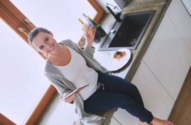 Gülümseyen kadın mutfakta tablet ve kredi kartı kullanarak alışveriş online .