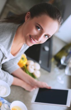 Gülümseyen kadın mutfakta tablet ve kredi kartı kullanarak alışveriş online .