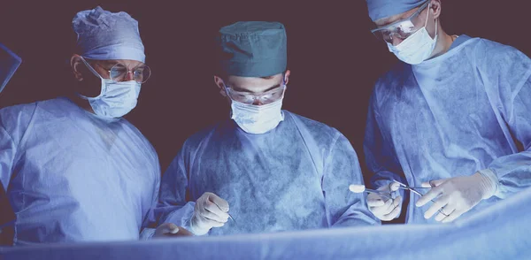 파란색으로 수술실에서 외과의들 일하고 있습니다 수술을 수행하는 — 스톡 사진