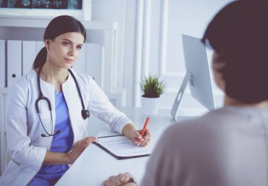 Doktor ve hasta acil serviste resepsiyon masasının yanında dururken bir şey tartışıyorlar.