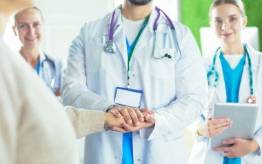 Doktorlar ve hemşireler tıbbi bir ekipte el ele tutuşuyorlar..