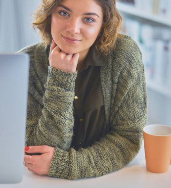 Öğrenci laptopla çalışıyor ve evdeki masada oturuyor..