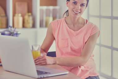 Mutfakta dizüstü bilgisayara benzeyen tariflerle gülümseyen genç bir kadın. Gıda blogcusu kavramı.