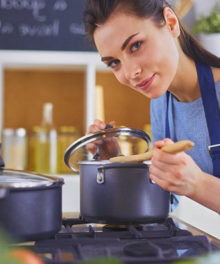 Mutfakta ahşap kaşıkla yemek pişiren kadın.