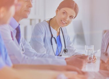 Parlak bir hastane odasında meslektaşlarıyla çalışan gülümseyen bir doktor.