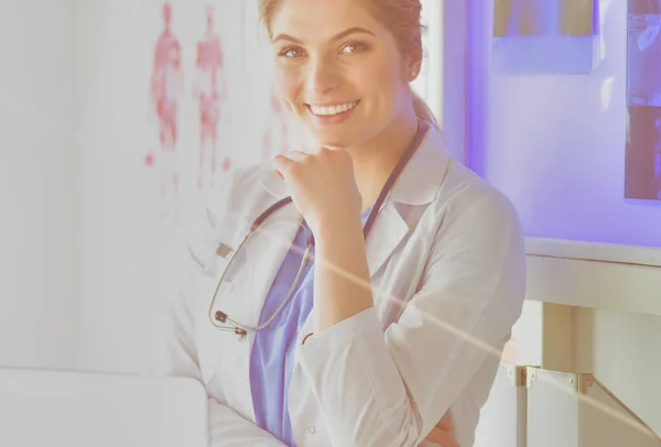 Young woman medic in white uniform standing in clinics office.